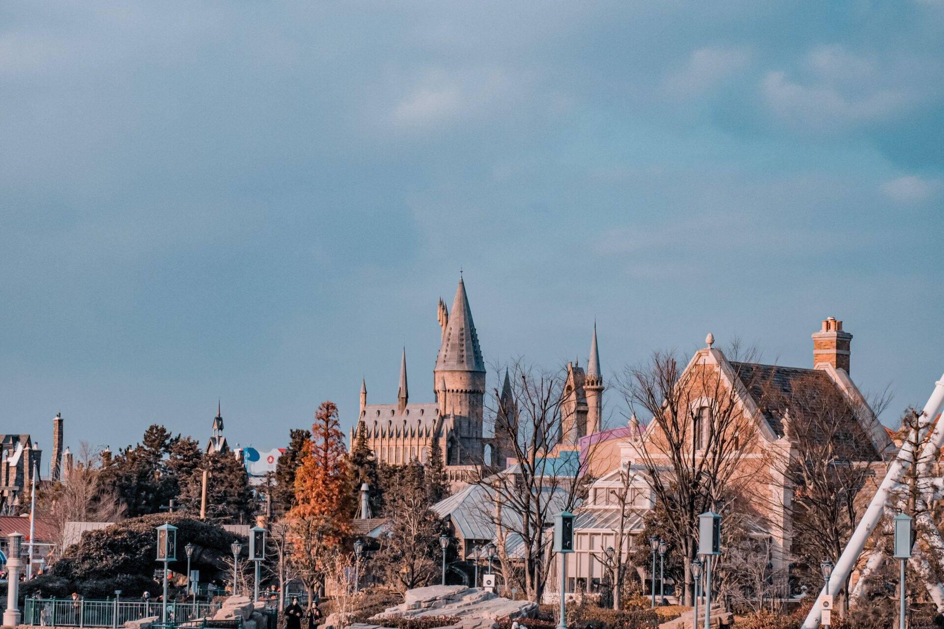 A Gothic-style castle with pointed towers surrounded by colourful buildings and autumn trees under a clear sky