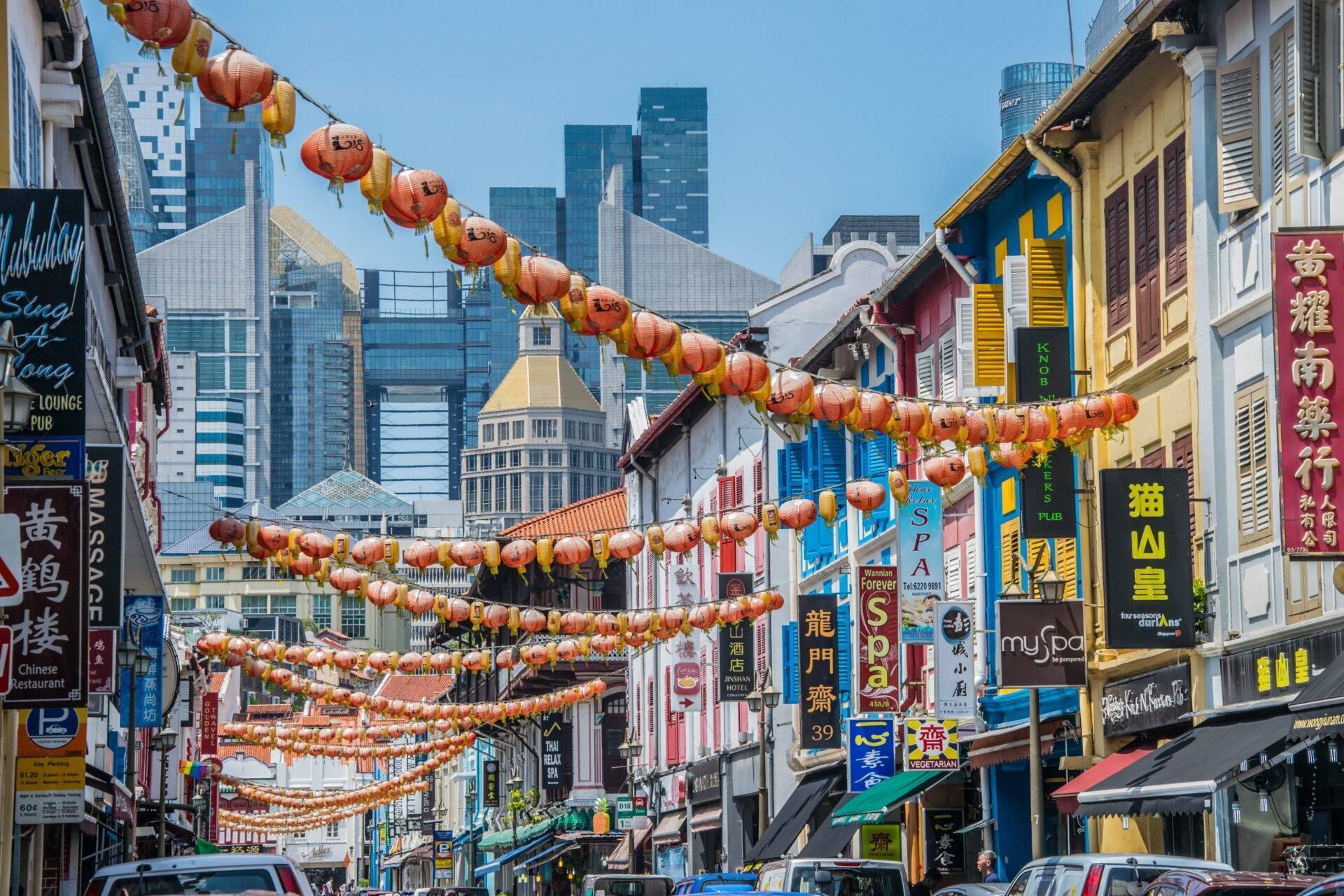 Une rue commerçante asiatique colorée décorée de lanternes rouges traditionnelles avec gratte-ciel modernes en arrière-plan