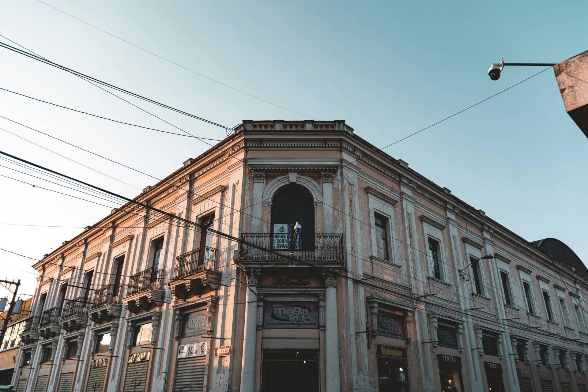 Un immeuble colonial aux façades colorées avec balcons en fer forgé et arcades commerciales au rez-de-chaussée